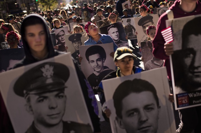 People carry photos of soldiers who died during the attack on Pearl Harbor. AP/Andres Kudacki