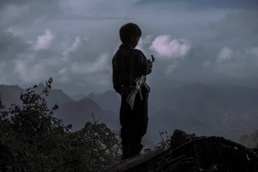 Chi Vang, de 10 años, contempla las montañas de Laos con un AK-47, en una imagen del documental "El Ejército Perdido de la CIA" (Sergio Caro).