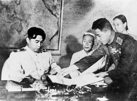 North Korean Premier Kim Il-sung prepares to sign the armistice handed to him July 27, 1953, by General Nam Il, head of the communist delegation at Panmunjom. (Eastphoto)